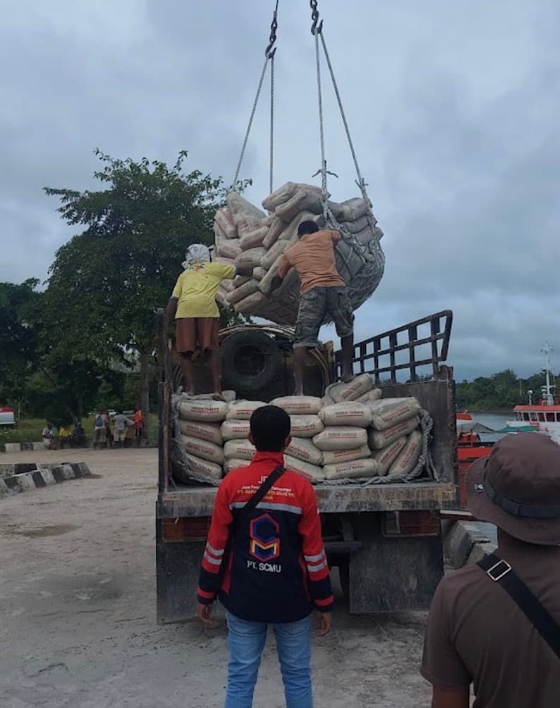 Pekerja mengarahkan pengangkatan muatan karung dari truk