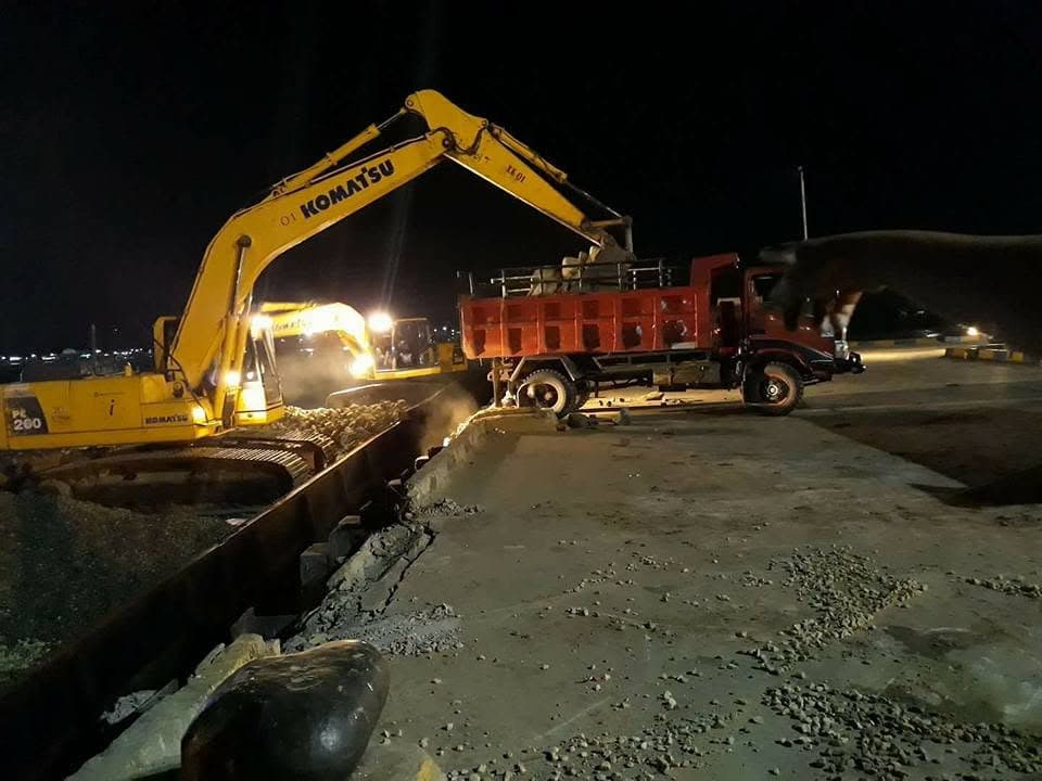 Ekskavator memuat material ke truk pada kegiatan malam hari